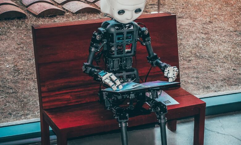 artificial intelligence (ai) berbentuk robot yang sedang duduk sambil memainkan tabnya